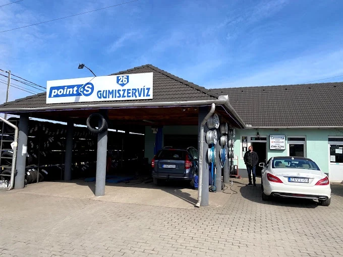 A 26-Gumiszerviz fedett szerelőállása Point S és 26 Gumiszervíz felirattal, abroncspolcokkal és felnikkel